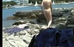 Naked girl walks on a rocky beach  